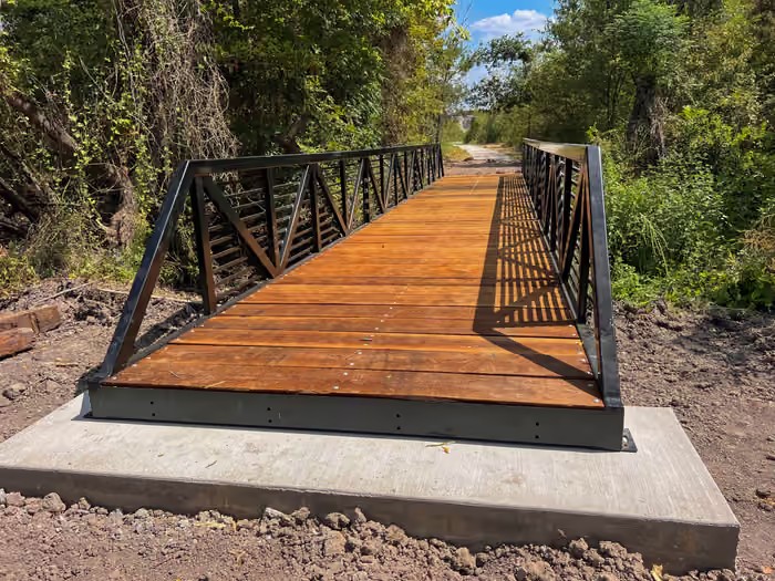 Steel bridge with timber decking spanning a wooded crossing